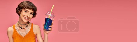 Téléchargez les photos : Jeune femme heureuse avec des cheveux bruns courts tenant boisson rafraîchissante d'été sur fond rose, bannière - en image libre de droit