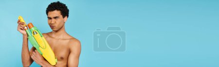 Photo for Handsome african american man posing with water gun and looking at camera on blue backdrop, banner - Royalty Free Image