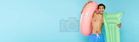 Téléchargez les photos : Homme afro-américain joyeux avec matelas gonflable et beignet gonflable souriant à la caméra, bannière - en image libre de droit