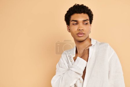 Téléchargez les photos : Raffiné chic homme afro-américain dans des vêtements blancs élégants regardant loin sur fond beige - en image libre de droit