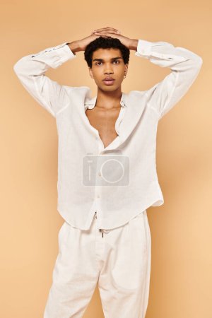 Foto de Elegante hombre afroamericano en traje blanco posando sobre fondo beige y mirando a la cámara - Imagen libre de derechos