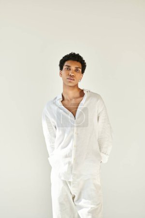 Foto de Buen aspecto joven afroamericano hombre en traje blanco y mirando a la cámara en el fondo beige - Imagen libre de derechos