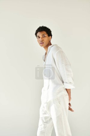 elegant appealing african american man in cozy outfit posing on beige backdrop and looking at camera