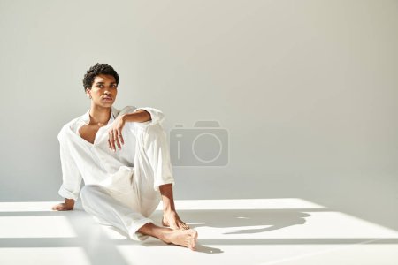 Photo for Handsome sophisticated african american man in linen attire sitting on floor and looking at camera - Royalty Free Image
