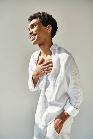 Téléchargez les photos : Joyeux modèle masculin afro-américain séduisant en lin blanc regardant loin sur fond beige - en image libre de droit