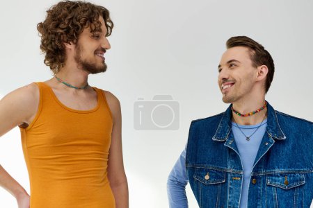 Photo for Appealing happy lgbt friends in vivid attires looking at each other on gray backdrop, pride month - Royalty Free Image