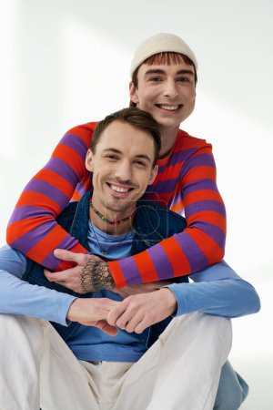 Photo for Two happy good looking lgbt friends in vibrant attires looking at camera posing on gray backdrop - Royalty Free Image