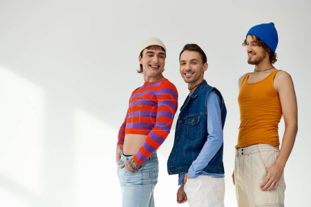 Photo for Joyful good looking lgbtq male friends in casual vibrant outfits posing actively on gray backdrop - Royalty Free Image