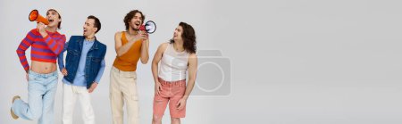 Photo for Four jolly gay men in stylish outfits using megaphones and posing actively on gray backdrop, banner - Royalty Free Image