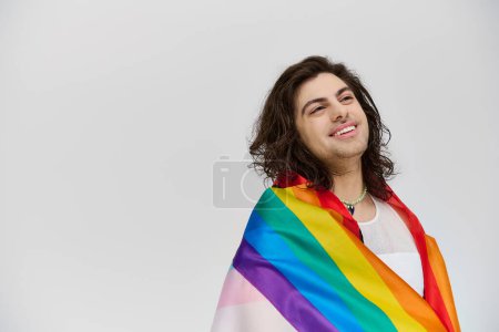 Téléchargez les photos : Beau fantaisie joyeux gay l'homme en vif tenue avec arc-en-ciel drapeau regardant loin sur gris toile de fond - en image libre de droit