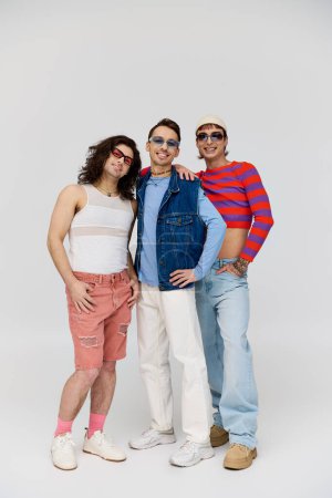 Photo for Three modish appealing gay friends in vibrant trendy attires with chic sunglasses, pride month - Royalty Free Image