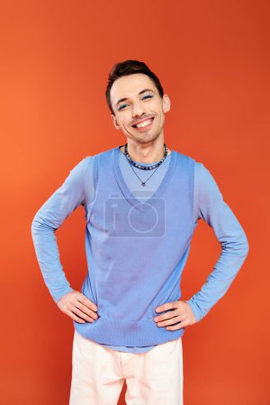 Photo for Mery attractive stylish gay man with vibrant makeup posing on orange backdrop, pride month - Royalty Free Image