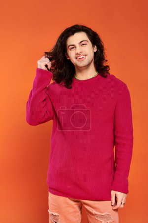 positiv gut aussehender schwuler Mann mit langen Haaren in magenta Sweatshirt, der in die Kamera schaut, stolzer Monat