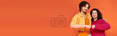 Photo for Jolly young gay friends in stylish vivid outfits posing together on orange backdrop, pride, banner - Royalty Free Image