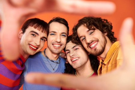 Photo for Four stylish appealing cheerful gay men in vibrant clothes posing together actively, pride month - Royalty Free Image