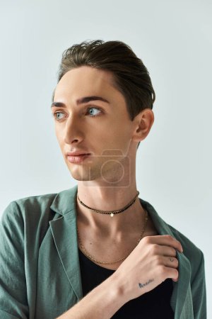 Photo for A young queer person with a vibrant green jacket strikes a pose in a studio setting against a grey background. - Royalty Free Image
