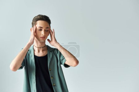 Photo for A young man, part of the LGBT community, stands with hands on head, expressing a moment of reflection and vulnerability. - Royalty Free Image