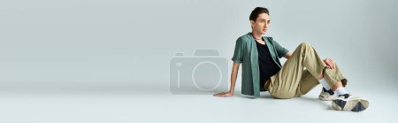 Photo for A young queer person with a proud look sits on the floor in a studio, showcasing his identity as a member of the LGBTQ+ community. - Royalty Free Image