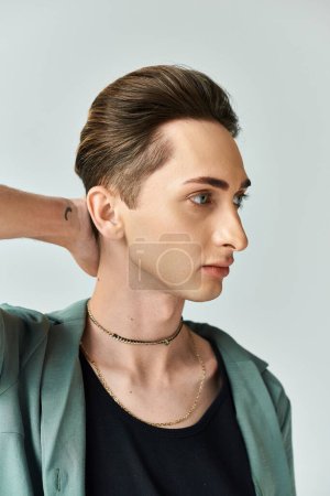 Ein junger queerer Mensch posiert stolz mit einer Halskette um den Hals in einem Studio-Setting und strahlt Zuversicht und Stolz aus.