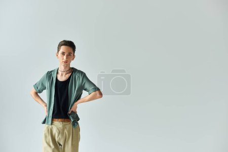 A young queer person strikes a pose in front of a white background, exuding confidence and pride as a member of the LGBTQ+ community.