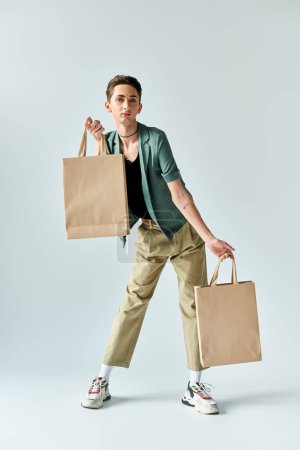 A young queer person proudly holds shopping bags against a white background.