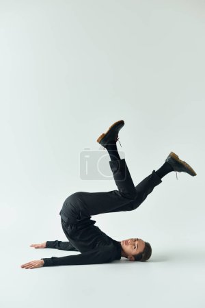 A young queer person showcases her strength and balance as she performs a handstand on a white background.