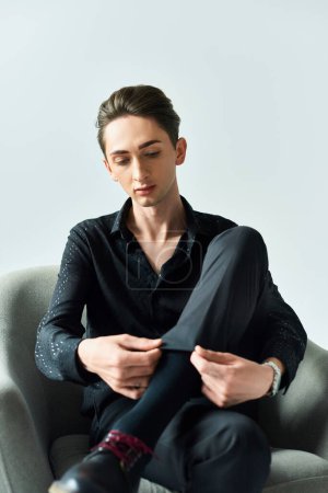 Un jeune homme sur une chaise attachant ses chaussures, avec un accent sur la fierté et l'expression de soi. Studio tourné sur un fond gris.