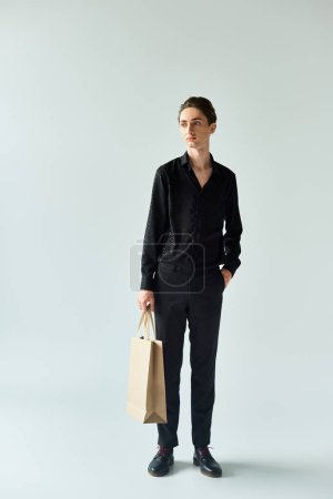 Photo for A young man proudly holds a shopping bag, expressing pride and joy - Royalty Free Image