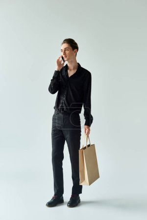 A queer person holds shopping bag, talks on phone. LGBT, pride.