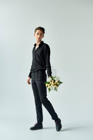 Téléchargez les photos : Un jeune queer se tient debout avec confiance, tenant un bouquet de fleurs, exsudant fierté et positivité. - en image libre de droit