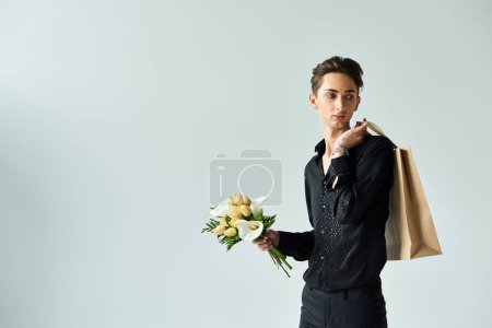 A young queer person confidently poses holding a shopping bag filled with flowers, expressing pride and joy.