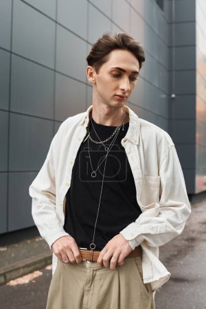 Foto de Un joven con estilo en una camisa blanca y pantalones bronceados emana confianza y orgullo. - Imagen libre de derechos