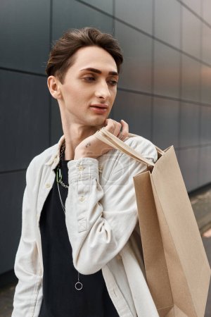 Ein stilvoller junger Mann mit Einkaufstasche steht vor einem modernen Gebäude.