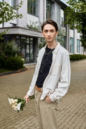 Foto de Un joven, vestido con estilo, se para frente a un edificio con un ramo de flores. - Imagen libre de derechos