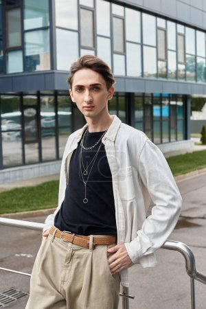 Ein stilvoll gekleideter junger Mann posiert vor einem modernen Gebäude und strahlt Zuversicht und Stolz aus.