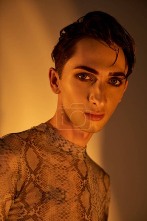 Ein junger Mann, der stolz ein Oberteil aus Schlangenhaut trägt und seinen einzigartigen und stilvollen Ausdruck queerer Identität und Stolz zur Schau stellt.