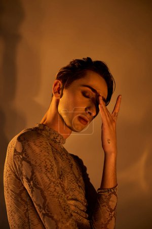 Photo for A young queer man, dressed stylishly, deep in thought with his hand on his face. - Royalty Free Image