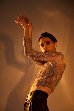 Foto de Una joven queer elegantemente vestida posa con los brazos extendidos en una muestra de confianza y orgullo. - Imagen libre de derechos