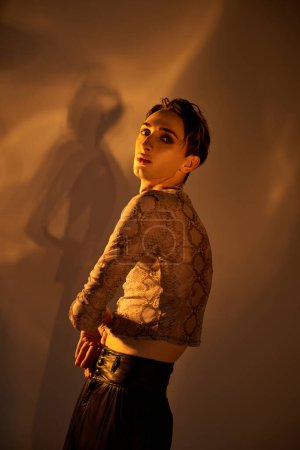 Foto de Una persona joven queer con un atuendo elegante se para con confianza frente a una pared, exudando orgullo y desafío. - Imagen libre de derechos