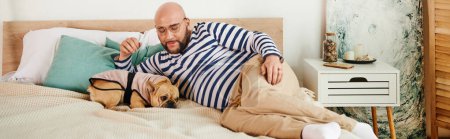 Hombre guapo con gafas pacíficamente se acuesta junto a su bulldog francés en una cama acogedora.