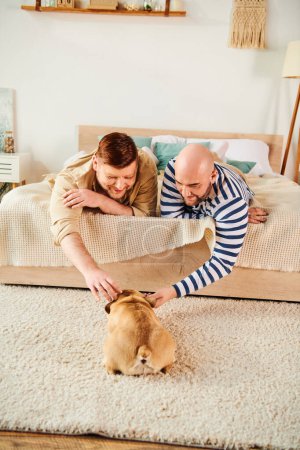 Photo for Two men laying on a bed next to a French bulldog, relaxing together. - Royalty Free Image