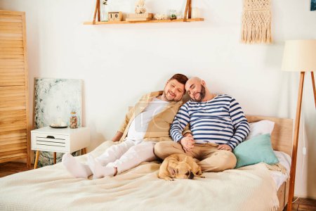 Photo for A gay couple, alongside their French Bulldog, lounging on a bed. - Royalty Free Image