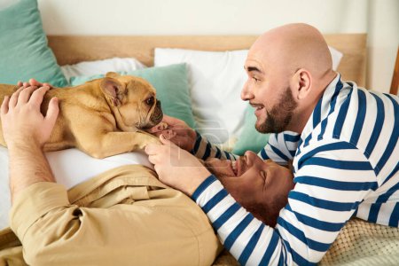 Foto de Dos hombres se relajan en la cama con su Bulldog francés. - Imagen libre de derechos