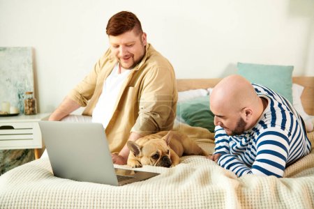 Photo for Two men and a dog lounging on a bed while using a laptop. - Royalty Free Image