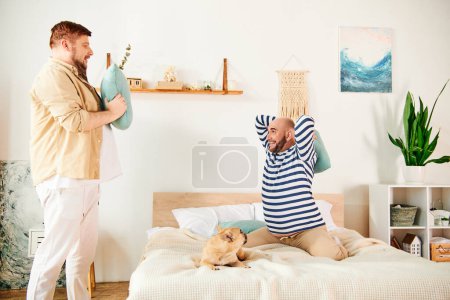 Photo for Two men standing together on a bed next to a French bulldog. - Royalty Free Image