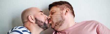 Ein schwules Paar drückt seine Zuneigung vor einer Mauer aus.