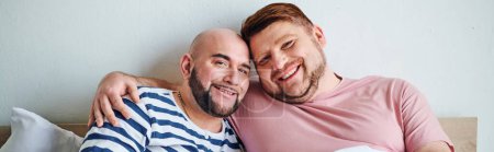 Foto de A gay couple sitting together on a bed. - Imagen libre de derechos