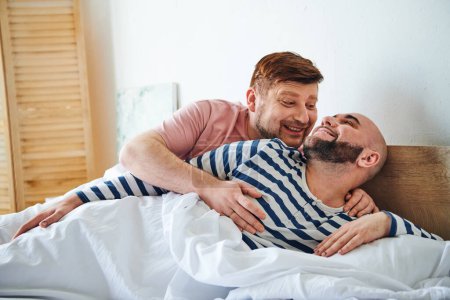 Two men snuggling in bed at home.