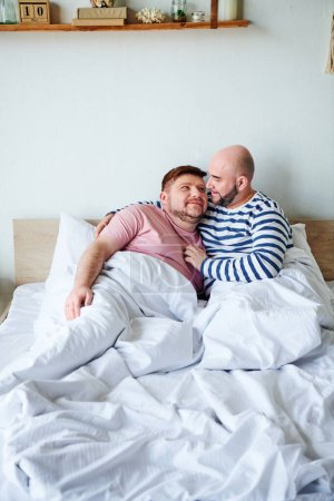 Two men relax on a bed at their home
