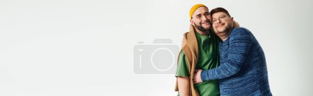 Photo for A duo of men stand lovingly on white backdrop. - Royalty Free Image